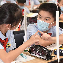 A few young boys wearing safety goggles and looking at a computer.