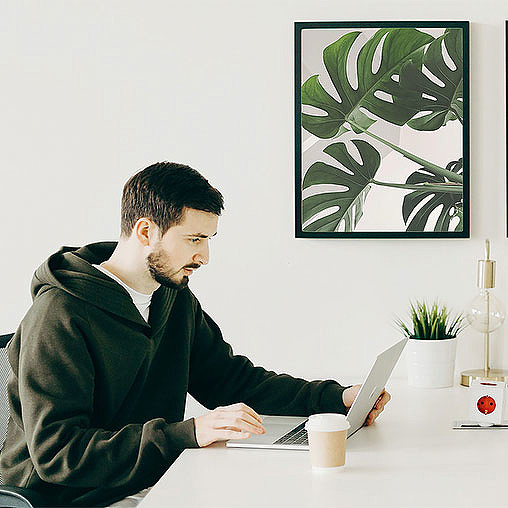 A person sitting at a table looking at a laptop.