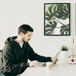 A person sitting at a table looking at a laptop.