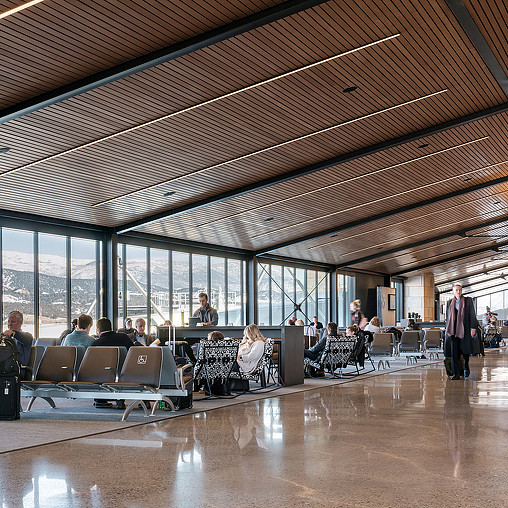 A group of people sitting in a room with large windows.