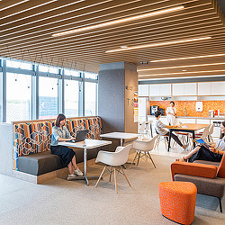 A group of people sitting in a room with orange chairs and tables.