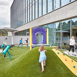 A group of children playing in a grassy area outside of a building.