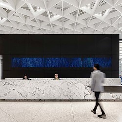 A person walking in front of a large glass wall.