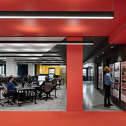 A person standing in a room with a person sitting at a table.