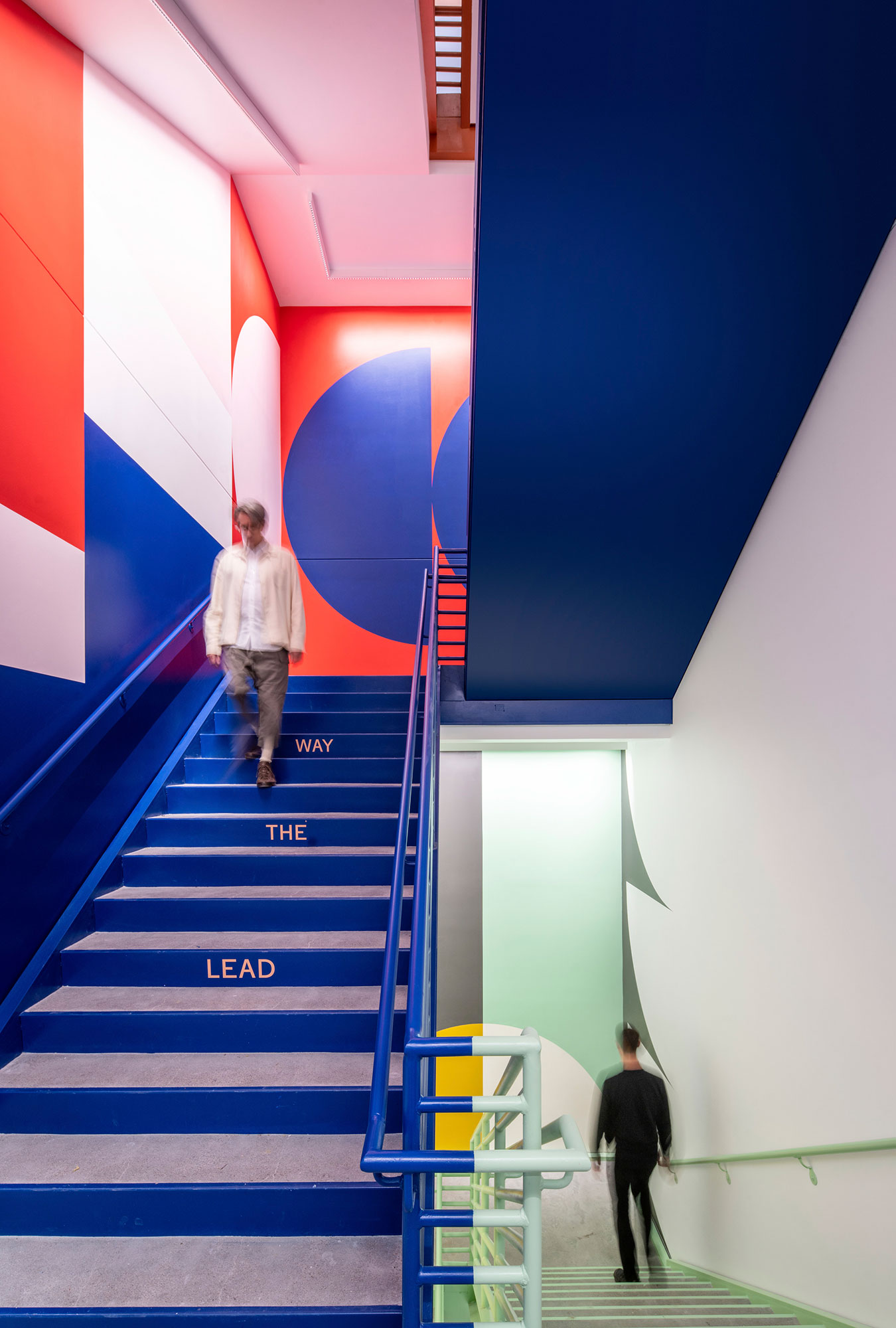 People walking in a company stairwell activated with graphics and murals.