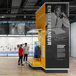 A man and woman standing next to a poster.