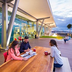 3 employees gathered around outdoor table at Gensler Costa Rica.
