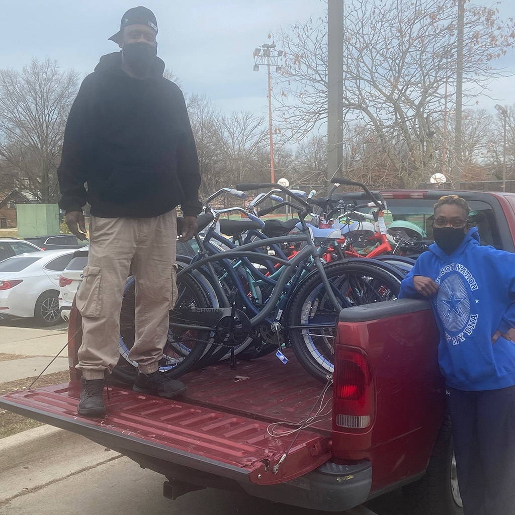 A man standing on the back of a truck with a bunch of bicycles on it.