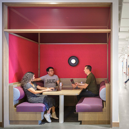 A group of people sitting at a table with laptops.