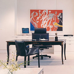 A desk with a laptop and chairs.