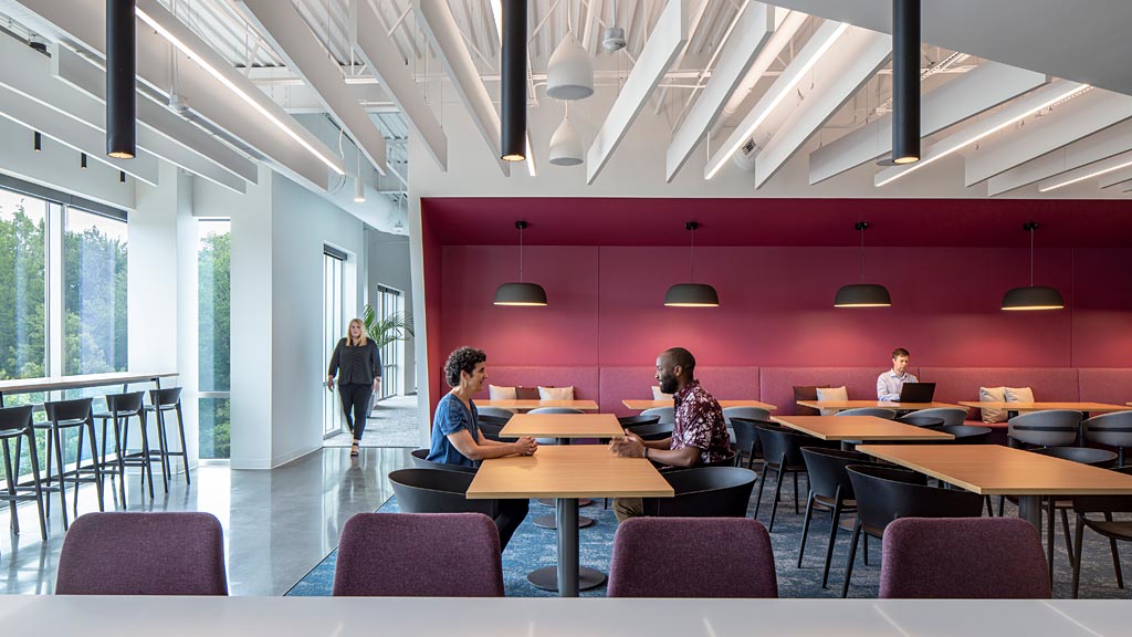 A group of people sitting at a table in a room with windows.