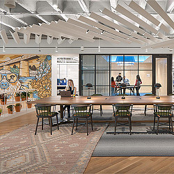 A group of people standing around a table with chairs in front of a large window.