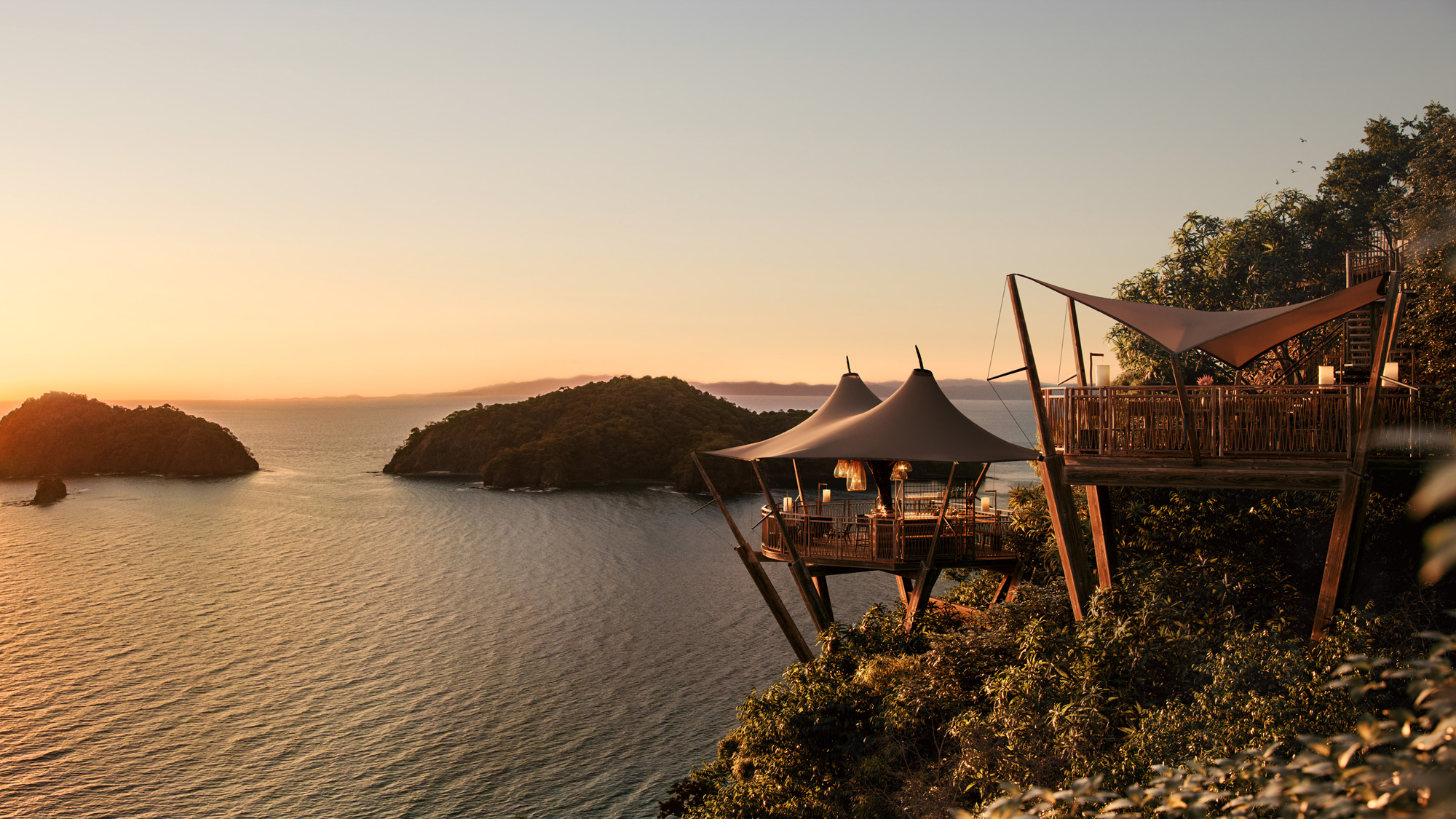 A table and chairs on a cliff above water.