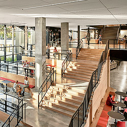 A modern wooden staircase with seating across multiple levels at Kentucky University Commons Helm Library