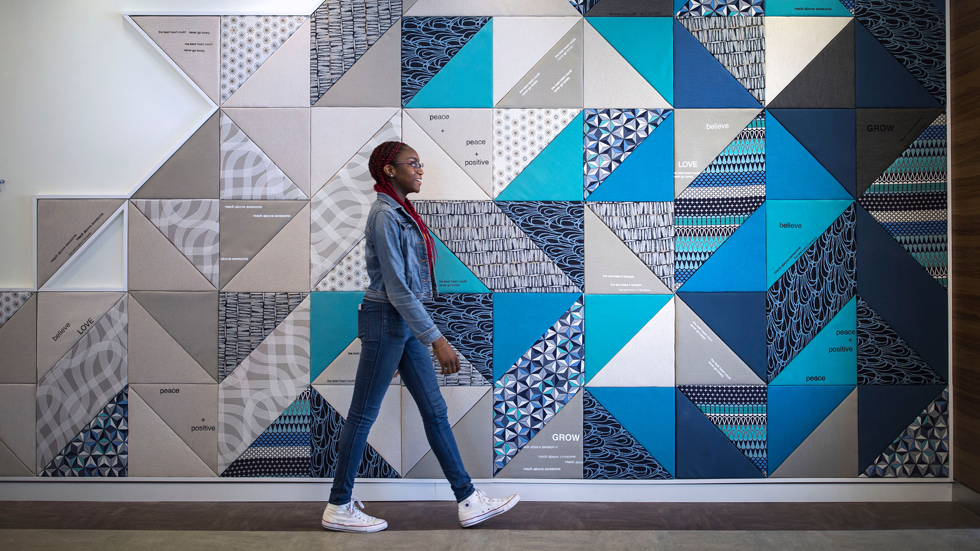 A person walks by a quilt wall.