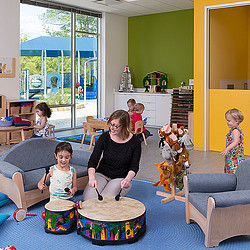 A person and a child playing with a dog in a living room.