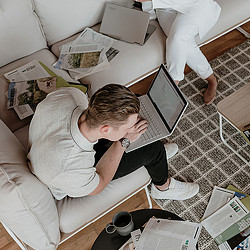 A person sitting on a couch using a laptop.
