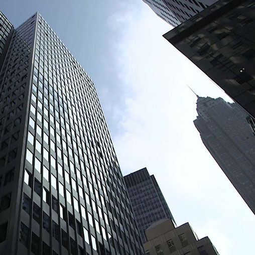City buildings with PBS New Hour logo in left corner