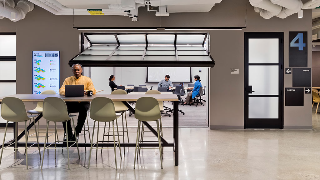 A group of people sitting at a table with laptops.