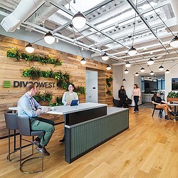 A group of people sitting at a table in a room with a ceiling of lights.