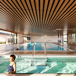 A person sitting on a balcony above a swimming pool.