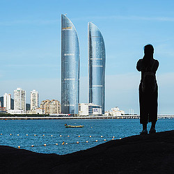 A shadow of a person standing on waterfront looking at Xiamen Shimao Straits Tower