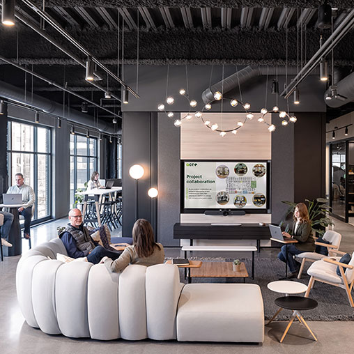 A group of people sitting in a room with a large screen.