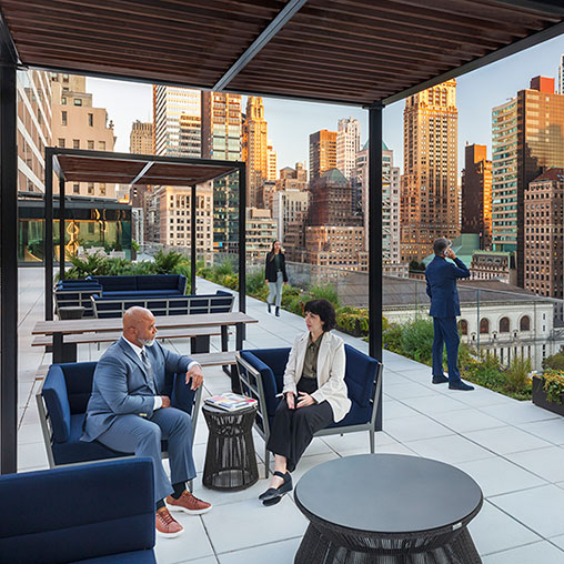 A man and a woman sitting on a bench in a room with a view of a city.