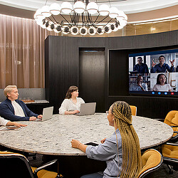 A group of people sitting around a table watching a television.