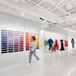 A group of people walking in a large room with white walls.