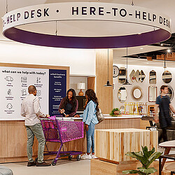 A group of people standing in a room with tables and chairs.