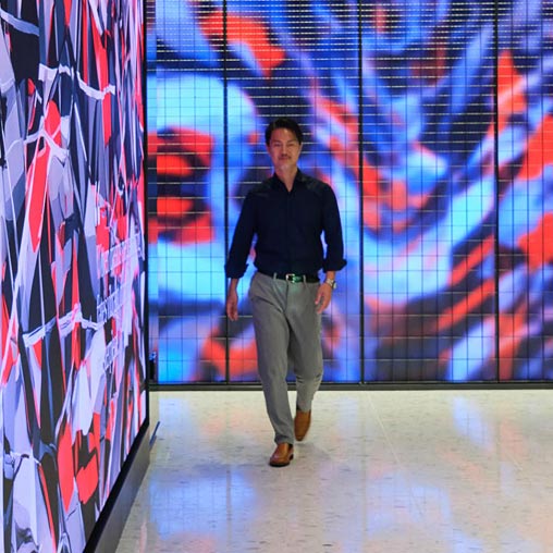 A man walking in a room with a wall of art.