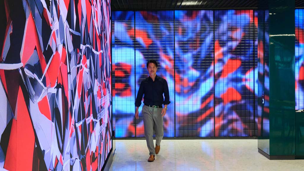 A person walking in front of a wall of art.