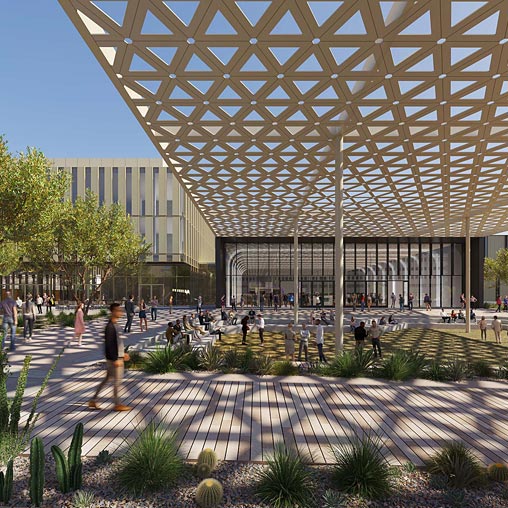 A large glass building with a courtyard and people walking around.