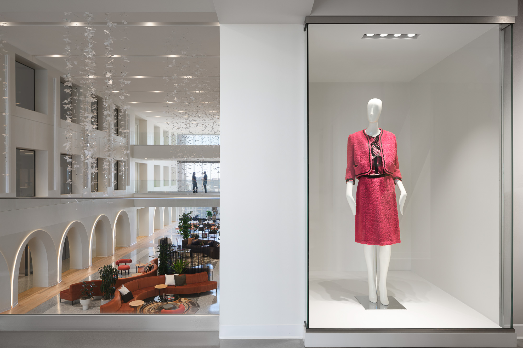 A mannequin in a pink matching skirt set in a display, and Neiman Marcus Group Dallas Hub atrium to the left