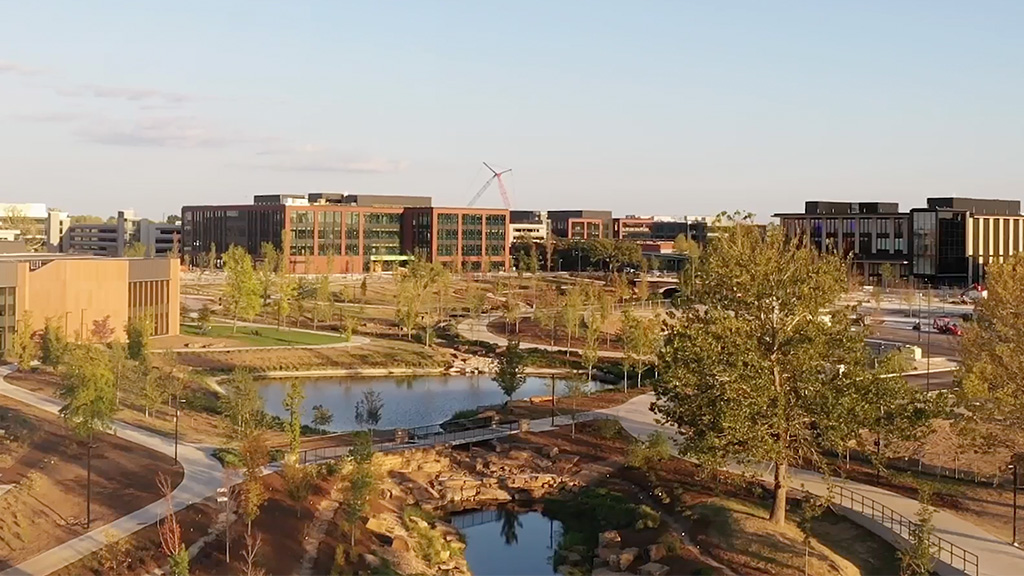 A park with a pond and buildings in the background.