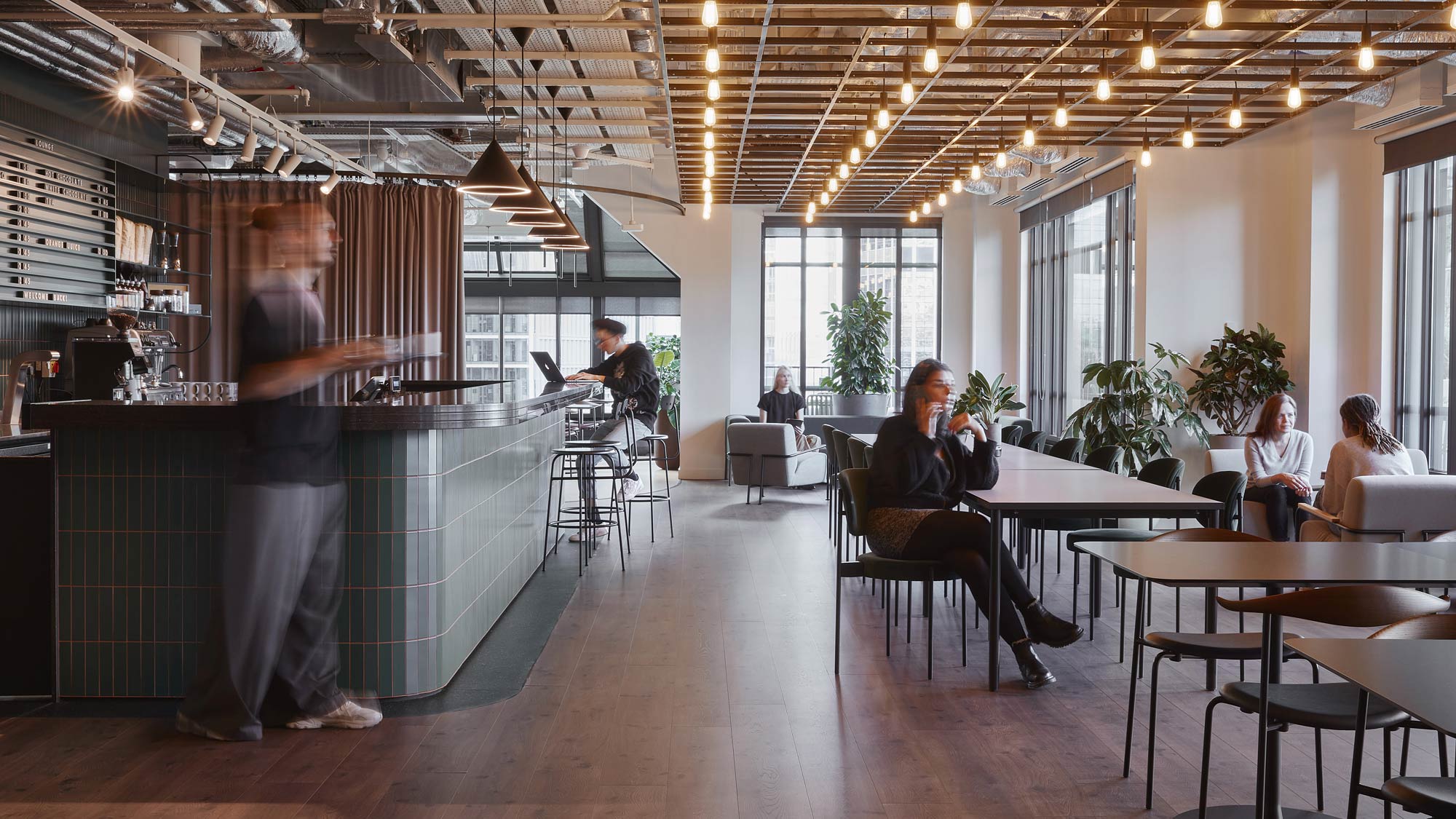 A person standing in a room with people sitting at tables.