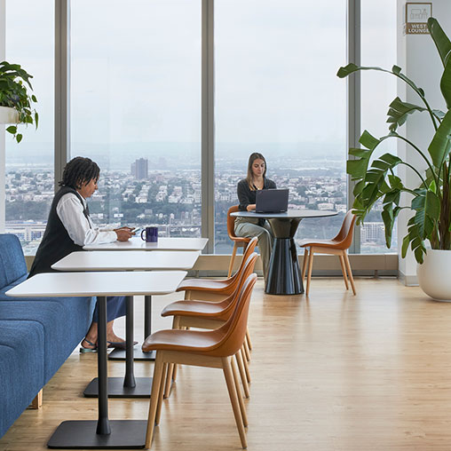 A couple of women sitting at a table with a laptop.