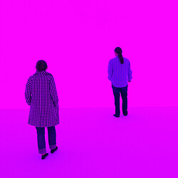 A woman and man standing in front of a hot pink James Turrell exhibit