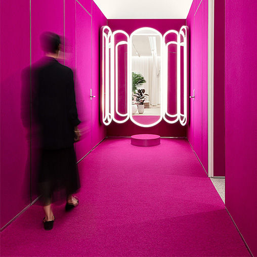 A person walking through a pink hallway.