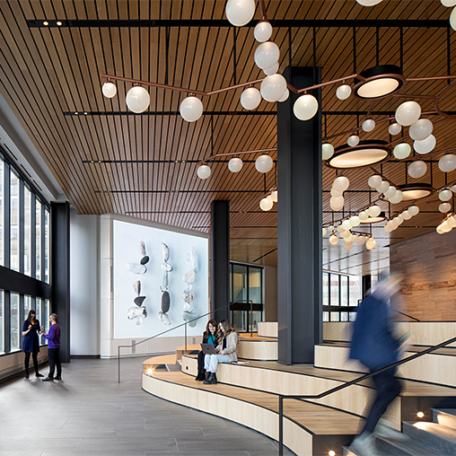 A group of people walking around a building with a large chandelier.