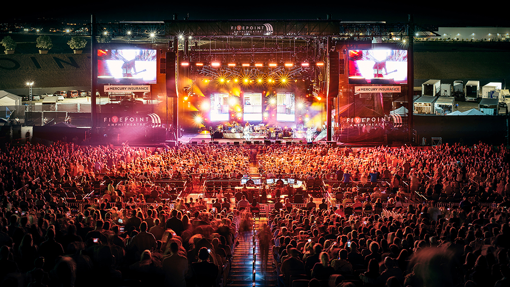 A large crowd of people in a room with large screens.