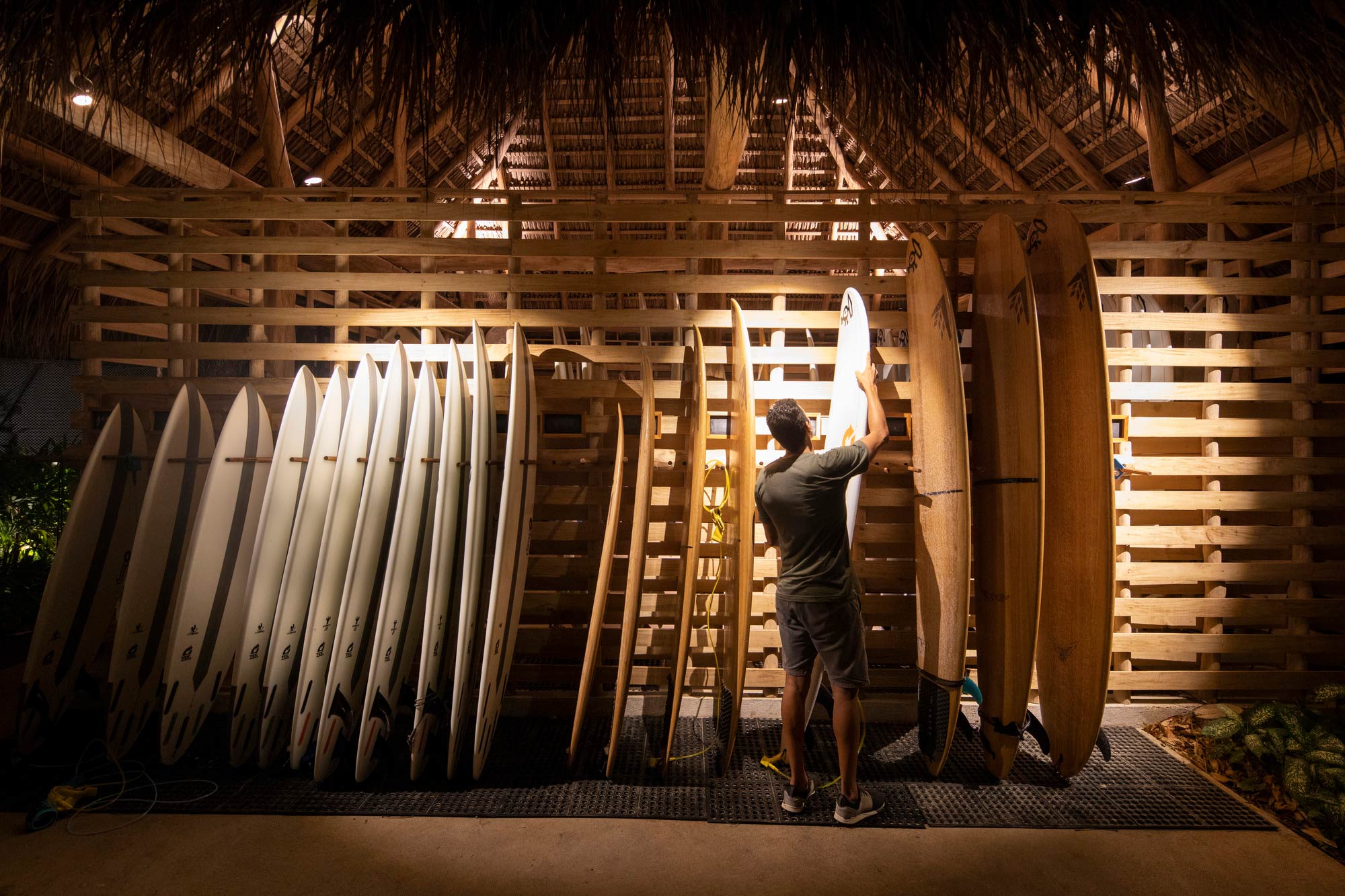 A person standing next to a row of surfboards.