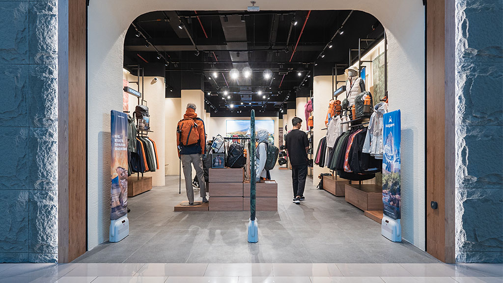 A group of people walk through a clothing store.