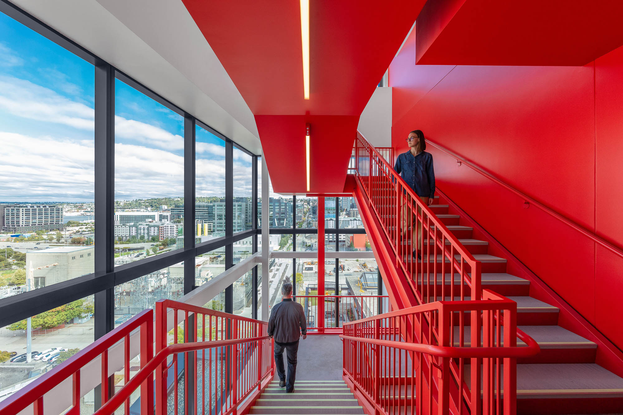 A man and woman walking up a red staircase.