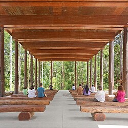 A group of people sitting on a bench under a covered area in Guulabaa.