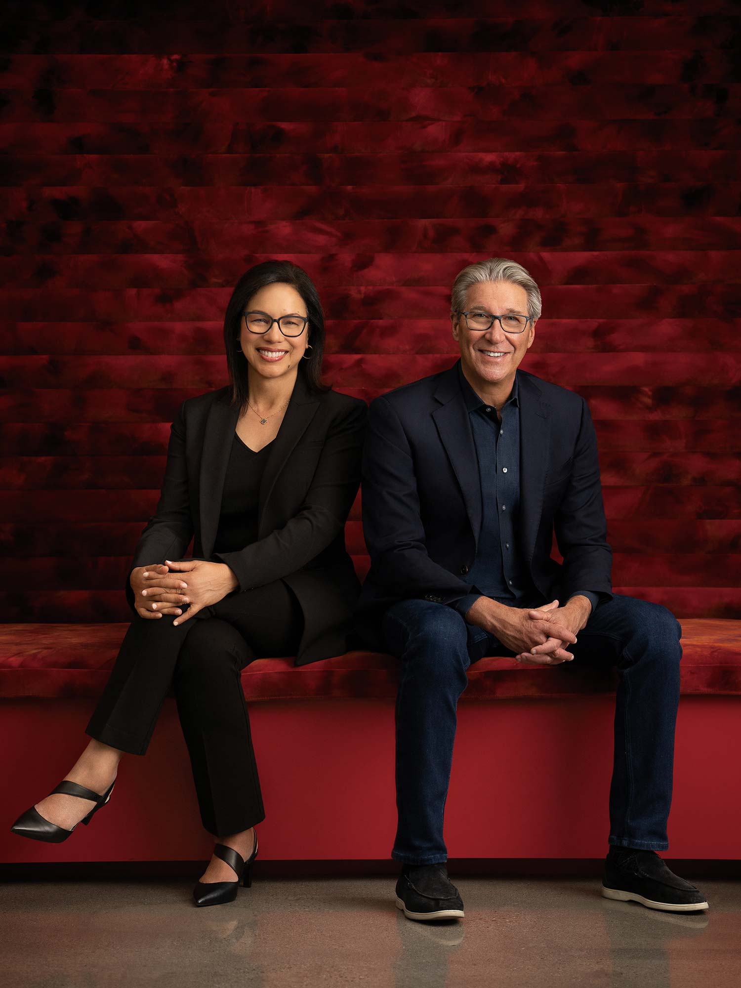 A man and woman sitting on a red couch.