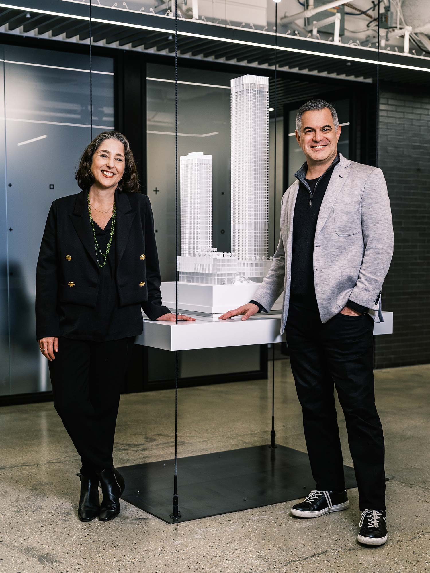 A man and a woman standing next to a display of computer monitors.