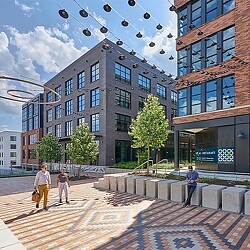 A group of people walking on a brick walkway next to a building.