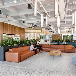 A couple of women sitting on a couch in a large room with a large glass ceiling and a.